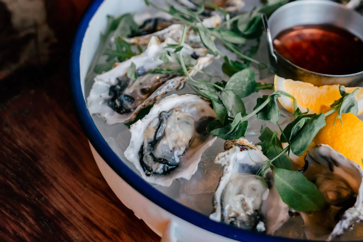 Freshly shucked oysters with lemon on a wooden board
