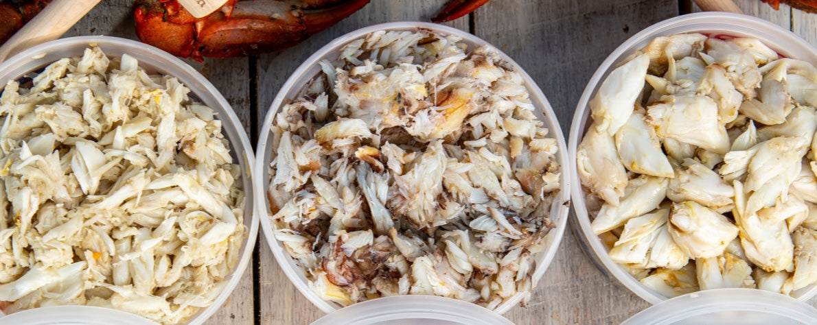 Lump, claw and jumbo lump crab meat in open tubs, side by side