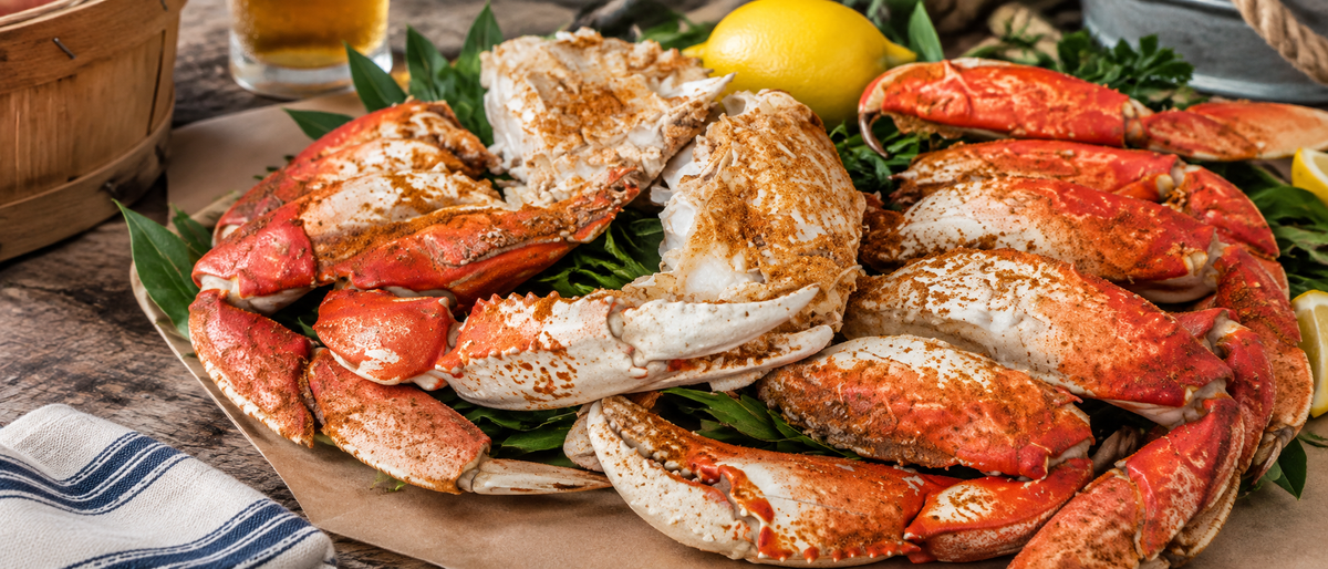 Platter of cooked Dungeness crab clusters with lemon