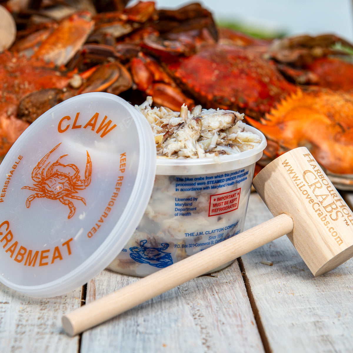 Open tub of Maryland claw crab meat with a crab mallet
