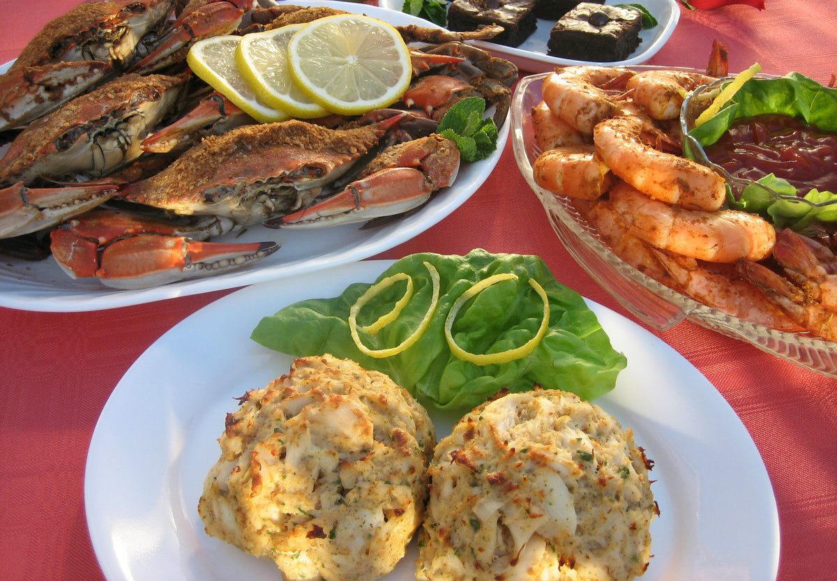 Steamed blue crabs, seasoned shrimp, two crab cakes and brownies on a table