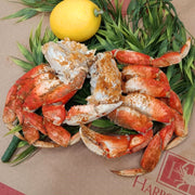 Colossal Dungeness crab leg clusters on crab paper with a lemon