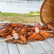 Steamed medium male blue crabs spilling from a bushel basket onto a deck