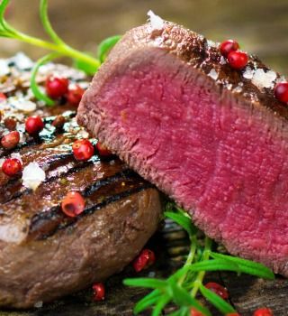 Grilled Angus beef tenderloin cut in half to show a pink center