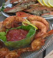 Seasoned jumbo shrimp with cocktail sauce, steamed blue crabs behind