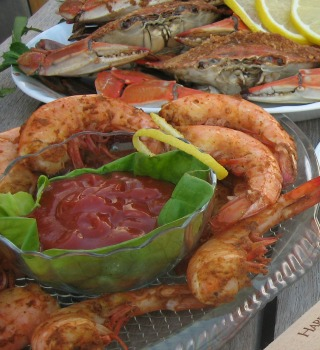 Seasoned jumbo shrimp with cocktail sauce, steamed blue crabs behind
