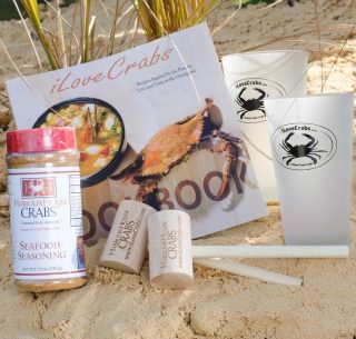 iLoveCrabs Cookbook propped on sand with Seafood Seasoning and two glasses