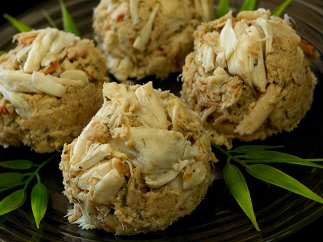 Four jumbo lump crab cakes on a dark plate showing chunky crab