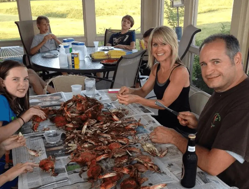 Family picking steamed blue crabs on newspaper on a screened porch